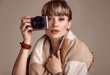 Portrait of beautiful glamour blond hippie woman taking picture on camera. Studio shoot