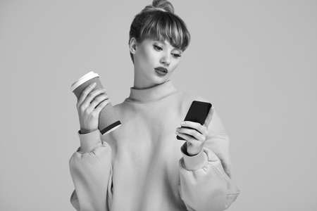 Portrait of beautiful glamour blond hipster woman with cup of coffee and phone. Studio shoot