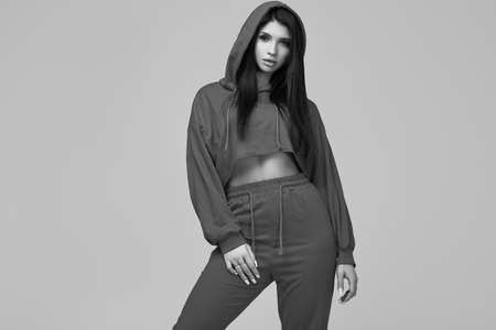 Portrait of gorgeous brunette woman in fashion red hoodie posing on studio backgroundの写真素材