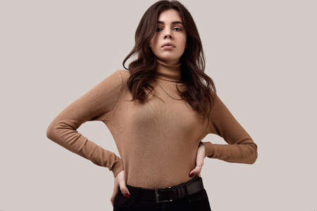 Portrait of fashion brunette woman wearing turtleneck and a gold chain isolated on white background in studioの写真素材