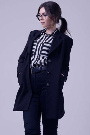 Portrait of fashion brunette woman wearing a striped blouse and black jacket isolated on white background in studioの写真素材