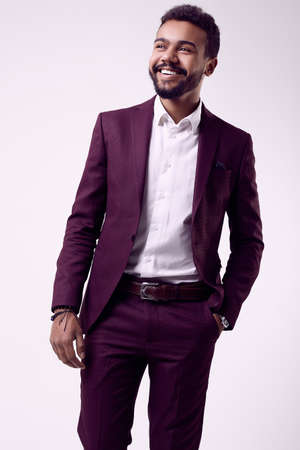 Portrait of cheerful brutal young African American male model in formal fashion suit isolated on white backgroundの写真素材