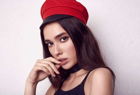 Close-up portrait of fashion brunette woman wearing a red hat isolated on white background in studio