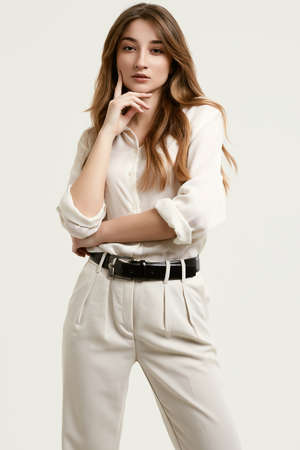 Portrait of gorgeous female brunette model posing in white fashion clothes in studioの写真素材