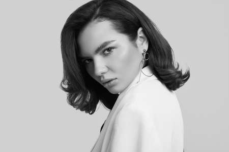 Studio portrait of attractive elegant caucasian woman with dark hair in fashion white suit isolated...
