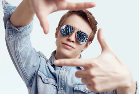 Portrait of handsome hipster man in fashion sunglasses wearing jeans jacket on white background in studioの写真素材