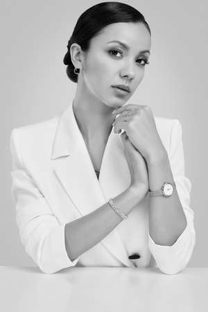 Portrait of a cute and gorgeous latin women in fashion white suit wearing expensive jewelry posing on bright studio backgroundの写真素材
