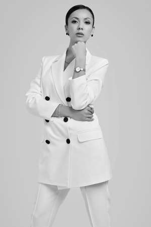 Portrait of a cute and gorgeous latin women in fashion white suit posing on bright studio backgroundの写真素材