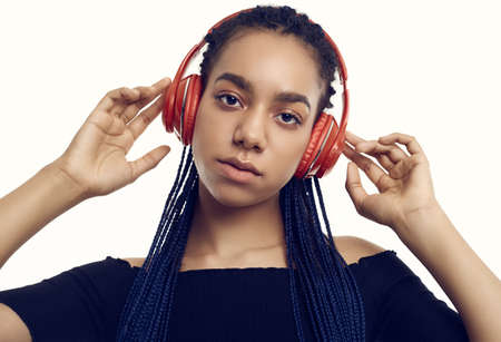Portrait of beautiful african brunette teenage girl with dreadlocks listening music via wireless...