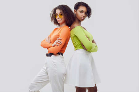 Portrait of two young beautiful hipster girls in trendy colorful summer clothes isolated on white background. Crazy positive bright teensの写真素材