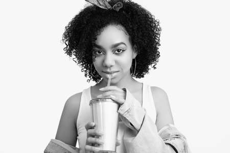 Sensual portrait of glamor elegant black hippie teenage girl model with curly hair drink soda isolated on white studio backgroundの写真素材