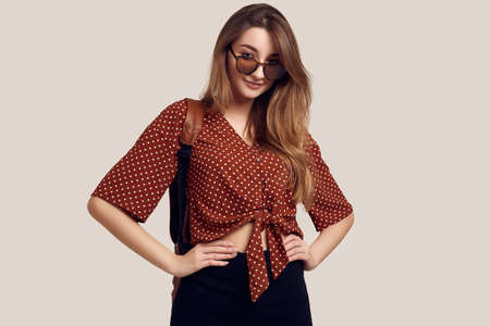 Portrait of young beautiful woman with backpack ready to travel. Smiling student girl going on a vacation. Isolated on gray background.の写真素材
