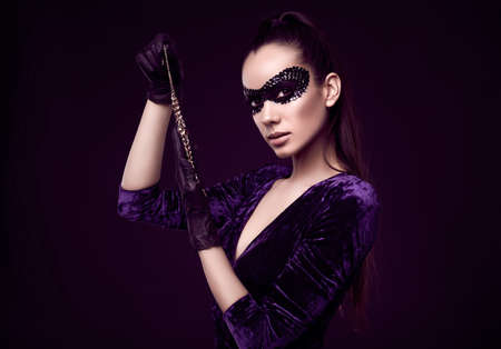 Portrait of charming elegant brunette woman in beautiful purple dress and sequins mask with black gloves looks at a stolen diamond necklaceの写真素材