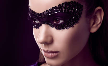 Close-up portrait of charming elegant brunette woman in sequins mask posing on black background in studioの写真素材