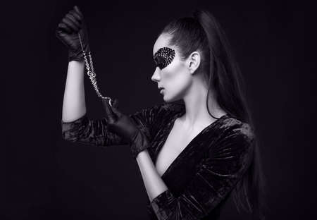 Portrait of charming elegant brunette woman in beautiful purple dress and sequins mask with black gloves looks at a stolen diamond necklaceの写真素材