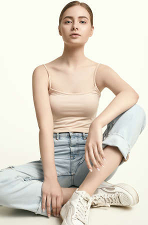 Portrait of attractive young brunette woman in jeans posing on white background studioの写真素材