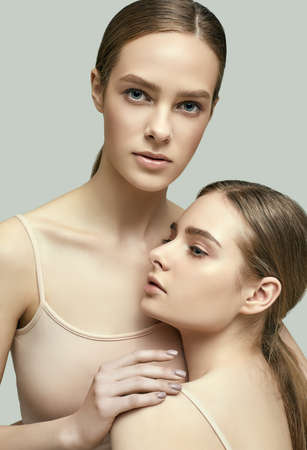 Studio portrait of two sensual young brunette girls with clear fresh face skin and perfect nude makeupの写真素材