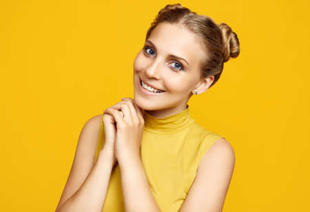 Positive portrait of gorgeous blonde hipster woman model with curly hair posing on colorful yellow...