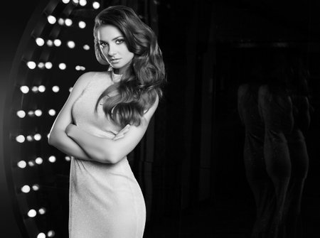 Portrait of gorgeous singer woman in elegant dress posing on restaurant stage spotlights background.の写真素材