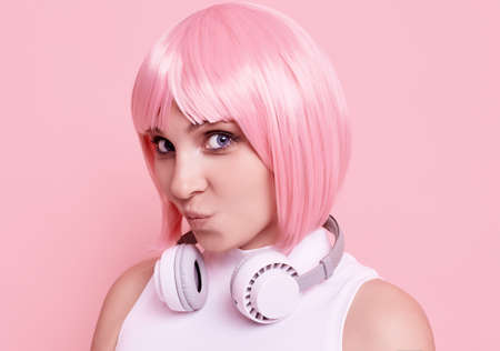 Portrait of gorgeous bright sexy hipster girl with pink hair enjoys the music in headphones on...