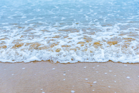 Soft wave of the sea on the sandy beach. Background and texture