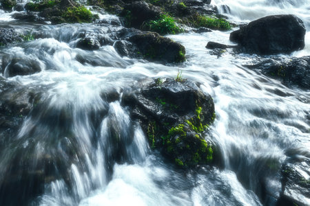 Long exposure of waterfall flowing over rocks with green moss in the foreground