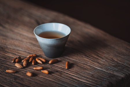 Cup of tea with pine nuts on old wooden background. Selective focus.の写真素材