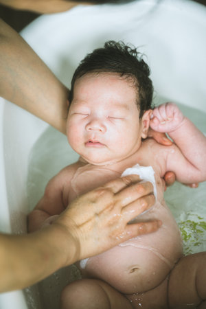 Mother washing her newborn baby in bathtub, shallow depth of field