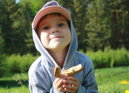 Funny little baby girl with a slice of bread on a Sunny dayの写真素材