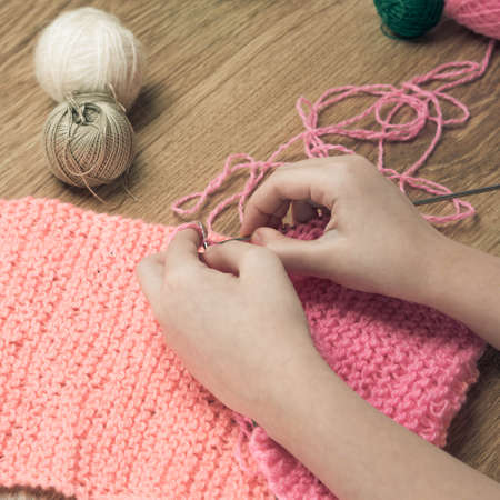 baby girl knitting pink scarf close up on a wooden table.の写真素材