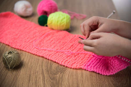 baby girl knitting pink scarf close up on a wooden table.の写真素材