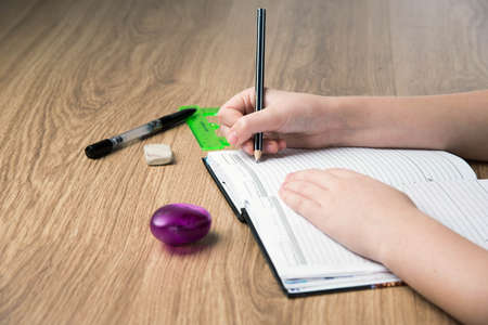 child hands writing in the album on wooden tableの写真素材