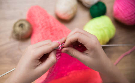 baby girl knitting pink scarf close up on a wooden table.の写真素材