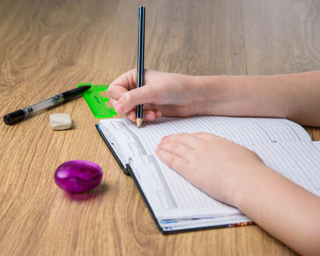 child hands writing in the album on wooden tableの写真素材