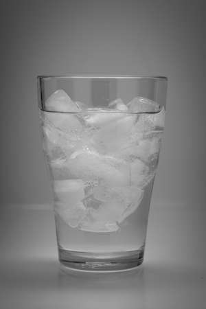 transparent glass with water and ice isolated on grey backgroundの写真素材