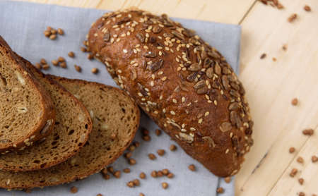 Fresh crusty bread on the plate and wheat ears on a wooden table