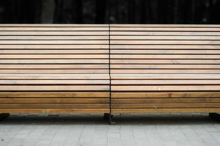 wooden Park bench closeup and track on a background of green bushesの写真素材