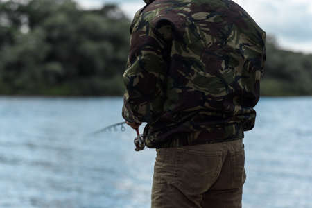fisherman with a feeder in front of a riverの写真素材