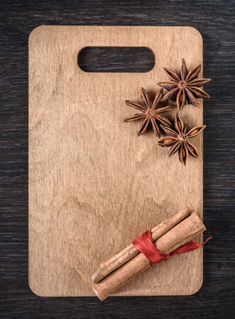 wooden cutting Board with star anise and cinnamon isolated on thedark backgroundの写真素材