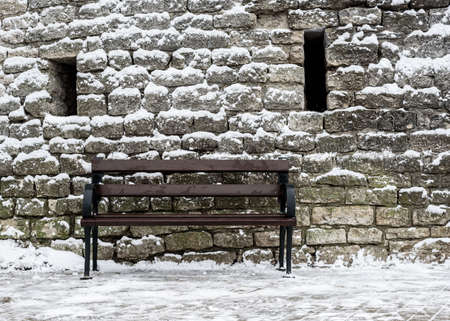 bench covered with snow in the background of the fortress wallの写真素材
