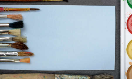 brush, paint white sheet of paper on a dark backgroundの写真素材