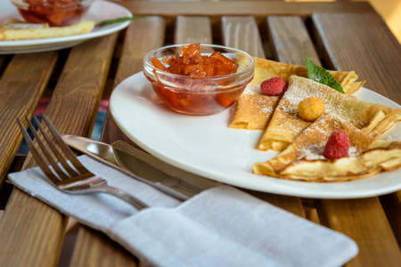 Crepes with jam, berries and sugar powder. Homemade pancakes, delicious breakfast on a wooden tableの写真素材