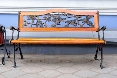 An empty wrought iron bench with wood accents against the blue wallsの写真素材
