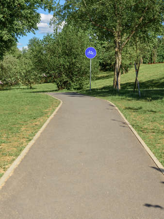 A Blue bike route sign on the side of the road in the summer Parkの写真素材