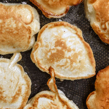 Square shot of delicious homemade pancakes frieding in a pan close-upの写真素材