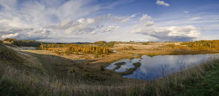 Horizontal shot of panorama of the Malsky valley and lake, the sun isilluminating autumn fields,...