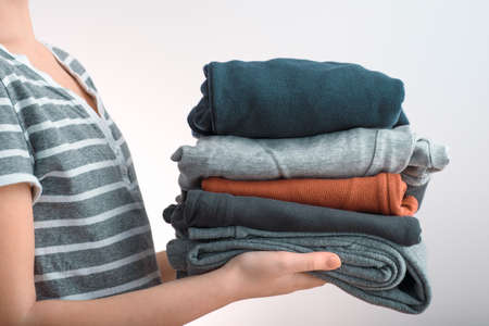 Horizontal shot of a Girl teenager holding a pile of clothes, isolated on gray backgroundの写真素材