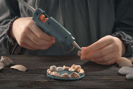 Woman make shell magnet with melt glue gunの写真素材