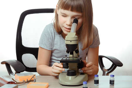 Teen girl in school laboratory. Researcher working with microscopeの写真素材