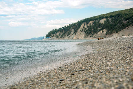 The coast washing by sea waves on the background of the mountain in the blur.の写真素材